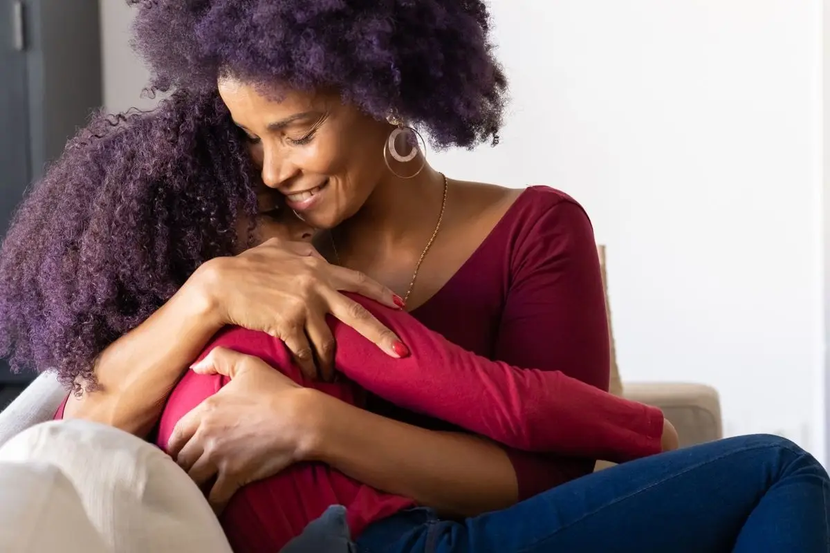 A mother and daughter sharing a hug on a sofa